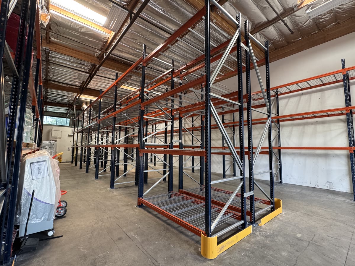 Seismic-rated selective pallet racking with blue uprights, orange beams, and yellow end-of-row guards in a Redlands, CA water storage facility